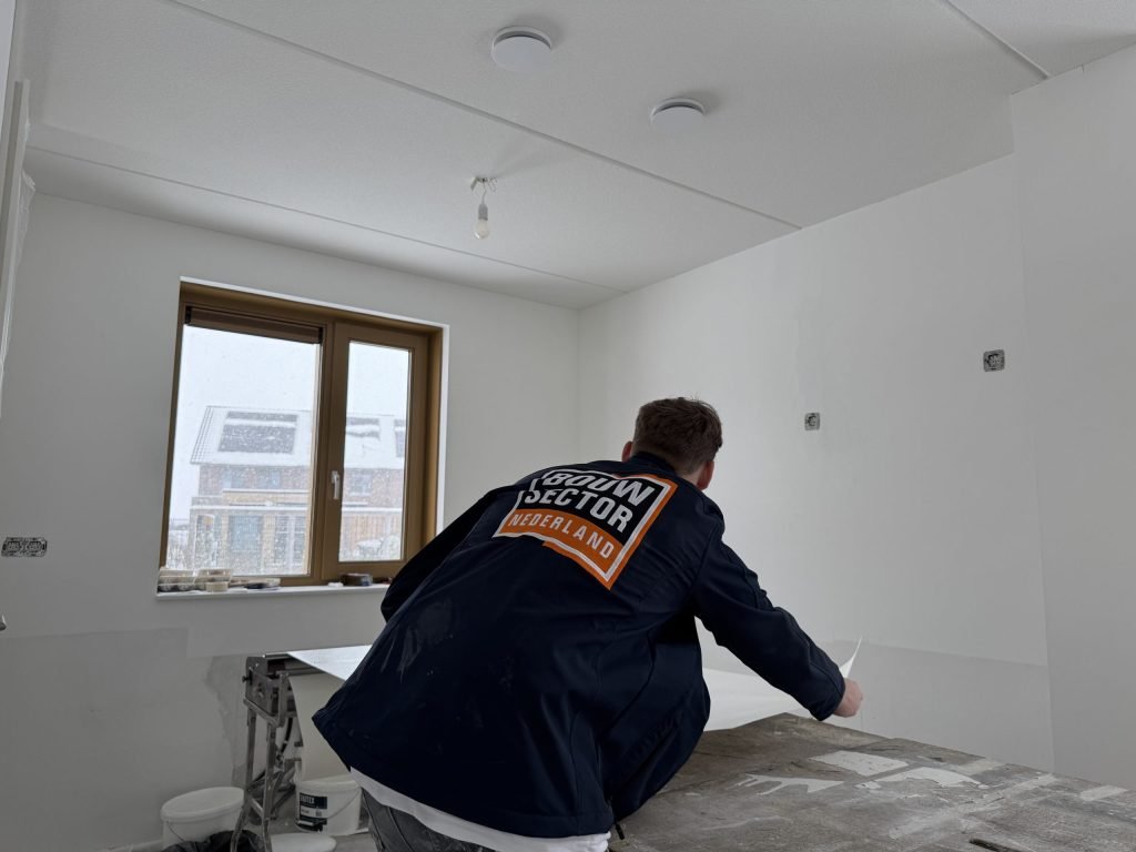 Vakman van Bouwsector Nederland aan de plaktafel in een kamer met kale witte wanden