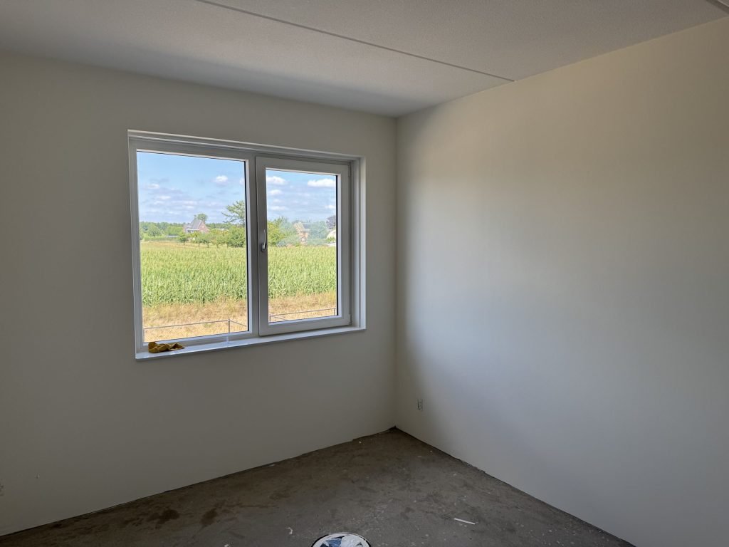 Kamer met gladde lichte wanden en een raam met uitzicht op een veld